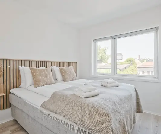 a bed with pillows and blankets in a room with windows