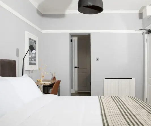 a bed with a striped blanket and a lamp in a room