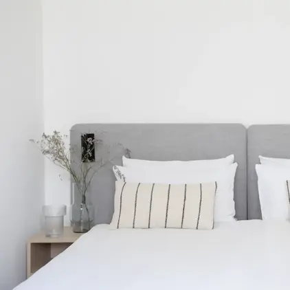 a bed with white sheets and pillows