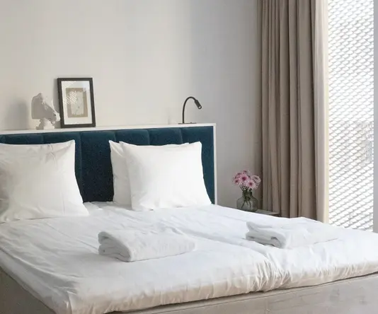 a bed with white sheets and towels
