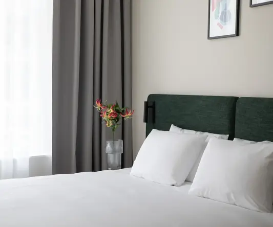 a bed with white sheets and a vase of flowers