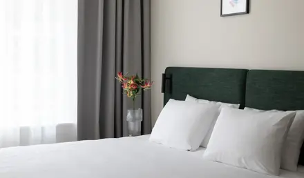 a bed with white sheets and a vase of flowers