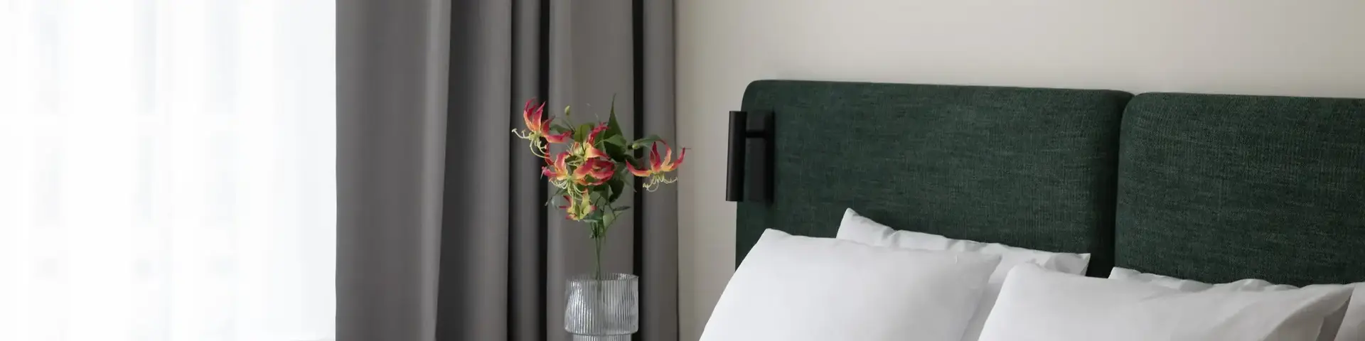 a bed with white sheets and a vase of flowers