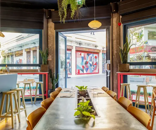 a table with chairs and plants in front of a glass door