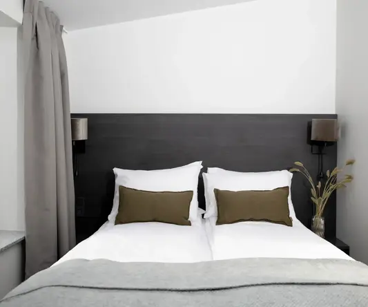 a bed with pillows and a vase of flowers