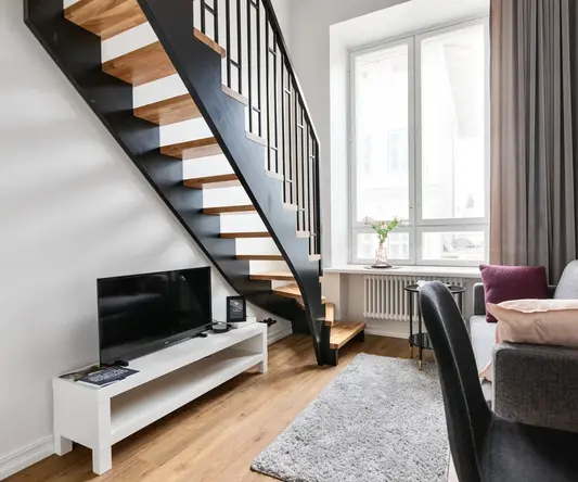 a living room with a staircase and a tv