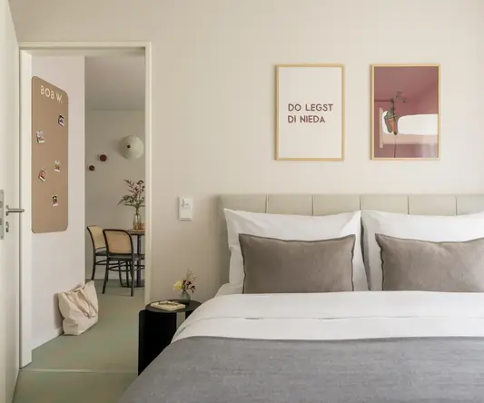 a bed with pillows and a table with chairs in the background