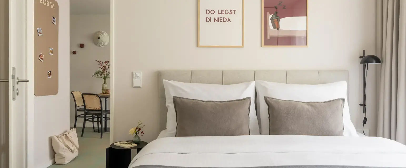a bed with pillows and a table with chairs in the background