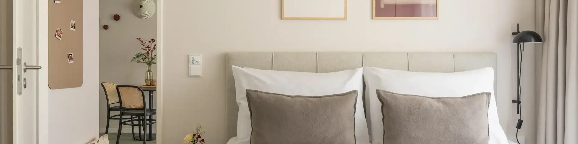 a bed with pillows and a table with chairs in the background