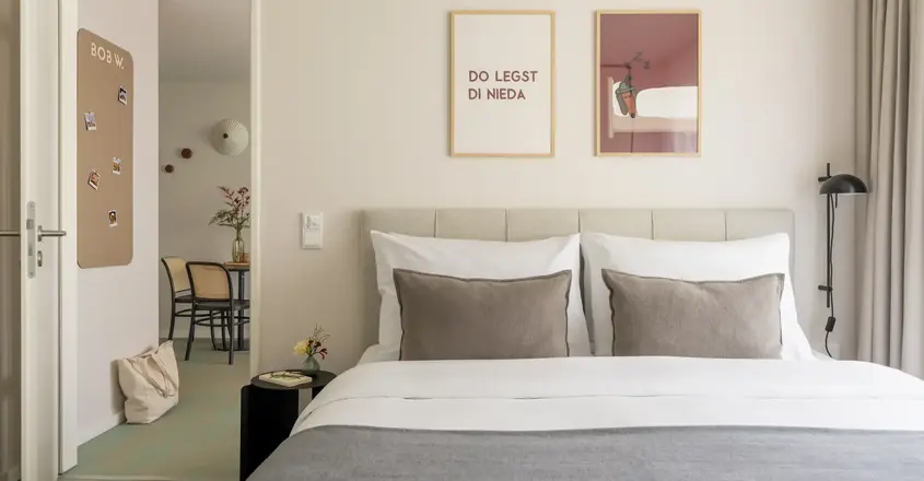 a bed with pillows and a table with chairs in the background