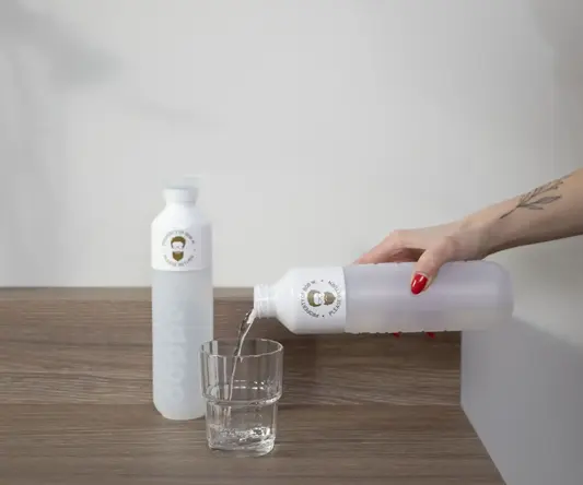 a hand pouring water into a glass