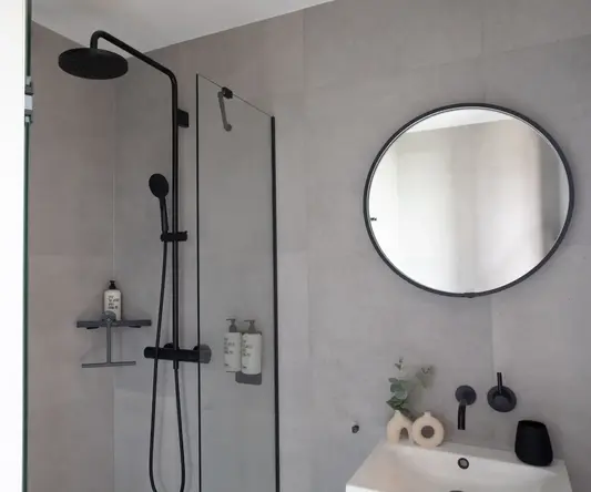 a shower with a round mirror and a round sink