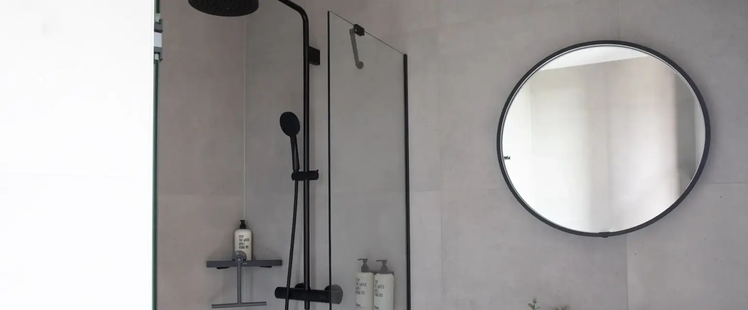 a shower with a round mirror and a round sink