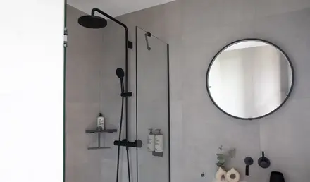 a shower with a round mirror and a round sink