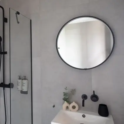 a shower with a round mirror and a round sink