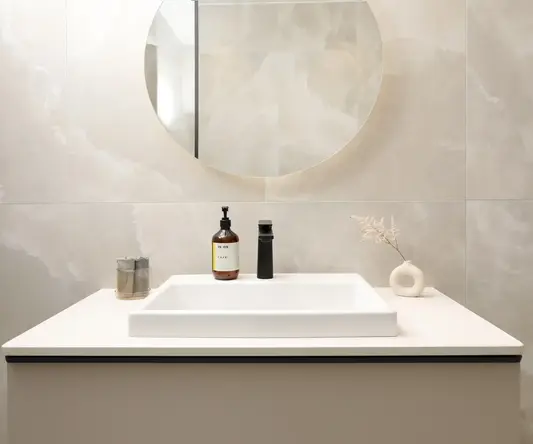 a bathroom sink with a round mirror