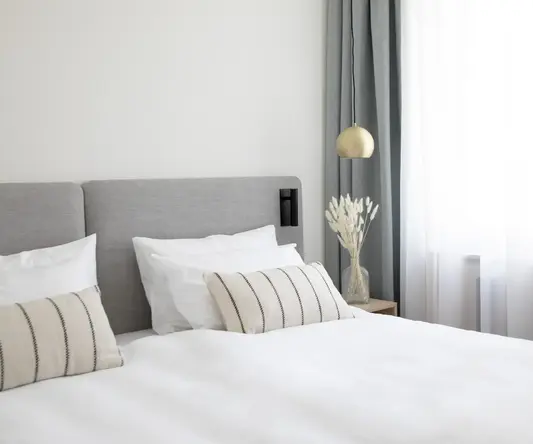 a bed with white sheets and pillows