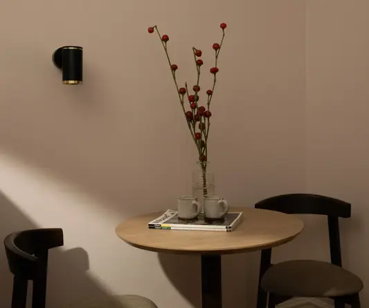 a table with a vase of red flowers and two cups on it