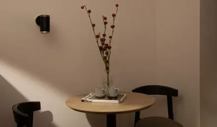 a table with a vase of red flowers and two cups on it