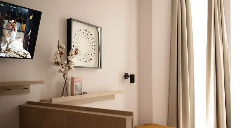 a bed with a yellow blanket and a vase of flowers on a shelf