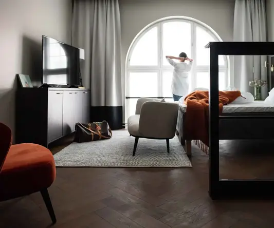 a man standing in a room with a bed and a chair