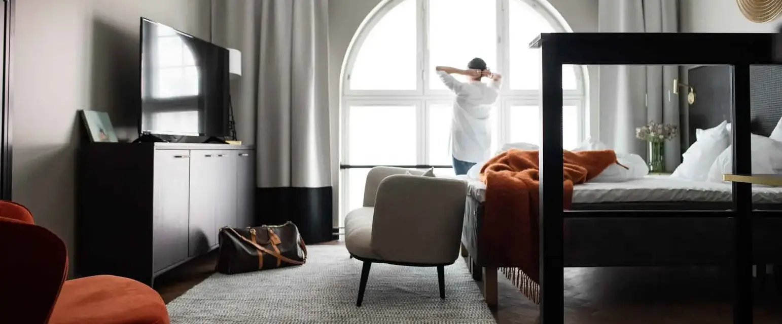 a man standing in a room with a bed and a chair