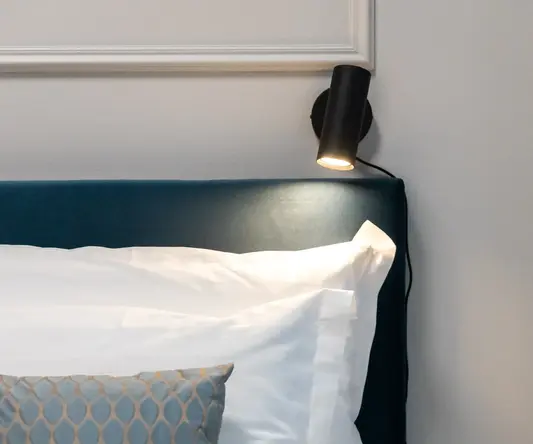 a bed with a lamp on the wall