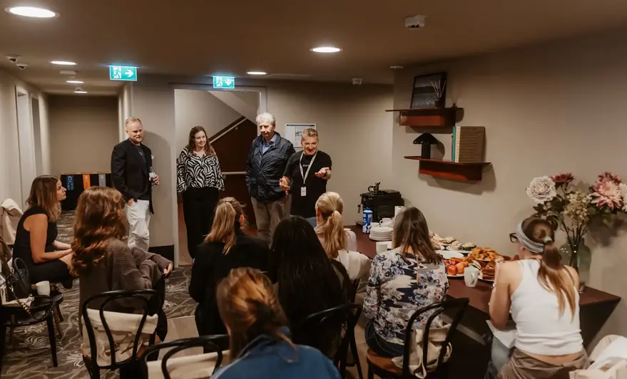 a group of people in a room with a table full of food