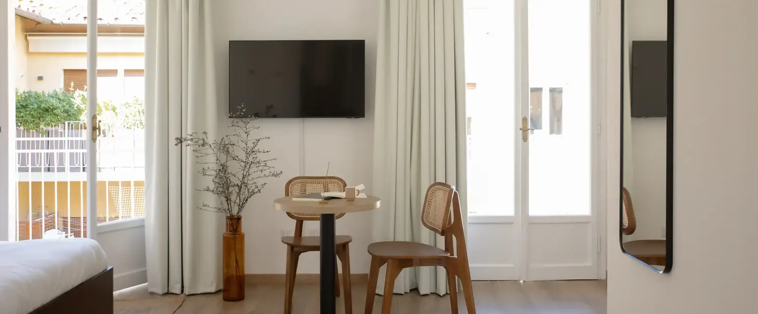 a room with a table and chairs and a television on the wall
