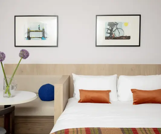 a bed with pillows and a vase of flowers