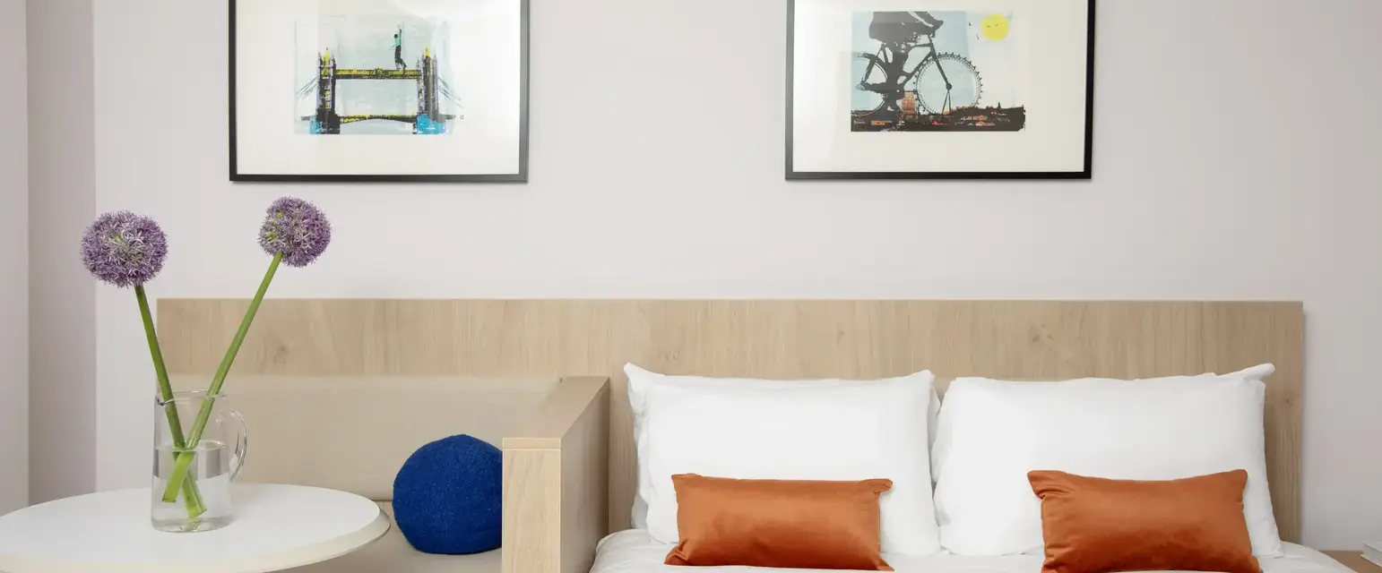 a bed with pillows and a vase of flowers