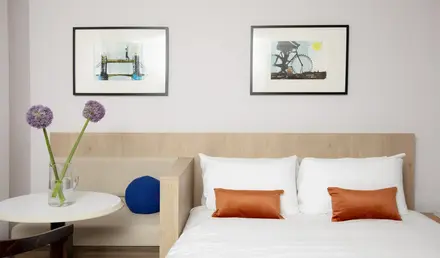 a bed with pillows and a vase of flowers