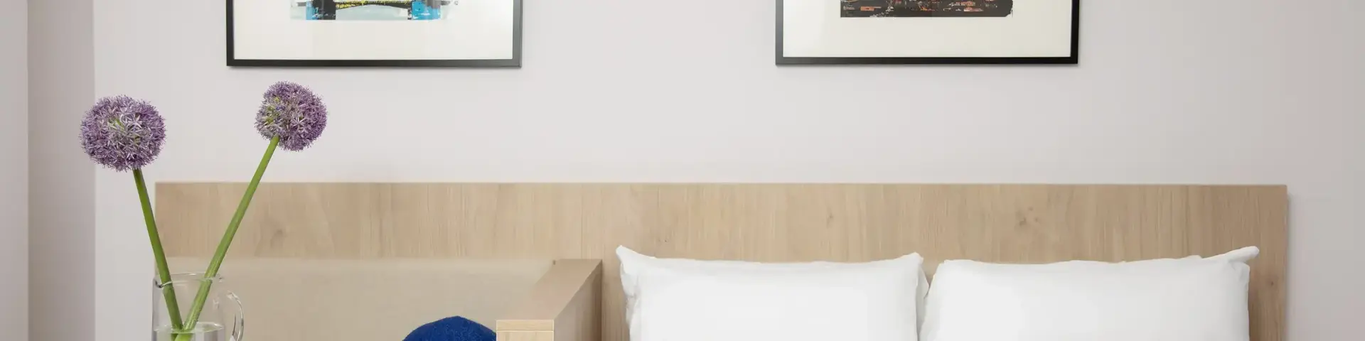 a bed with pillows and a vase of flowers