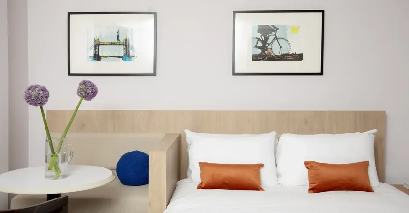 a bed with pillows and a vase of flowers