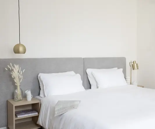 a bed with white sheets and pillows