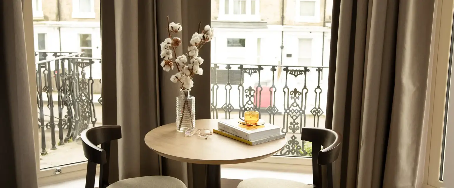 a table with a vase of cotton on it and a book on it