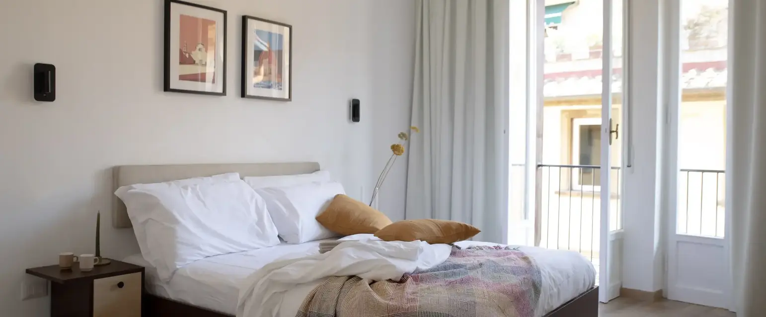 a bed with pillows and a blanket in a room with a balcony