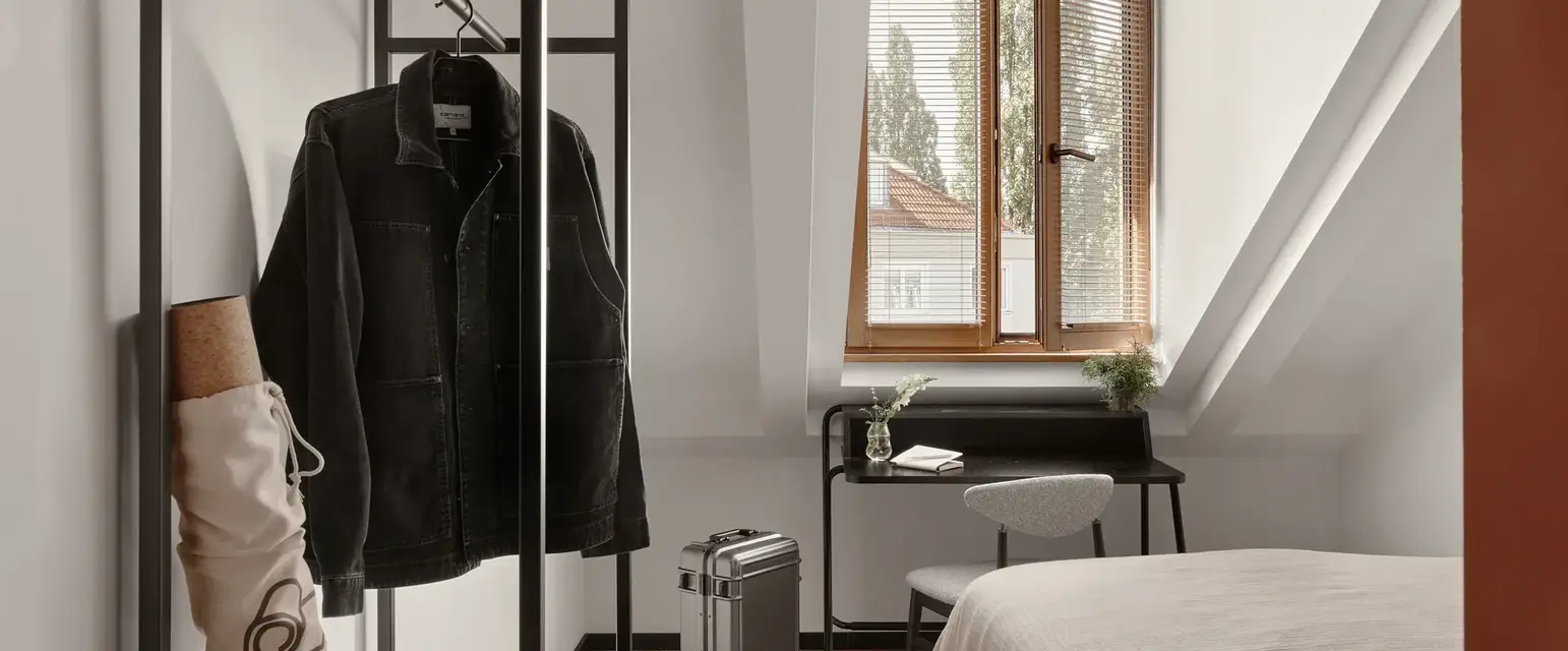 a room with a bed and a coat on a rack