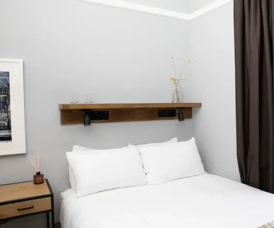 a bed with white sheets and brown curtains