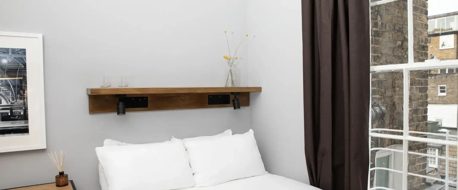 a bed with white sheets and brown curtains