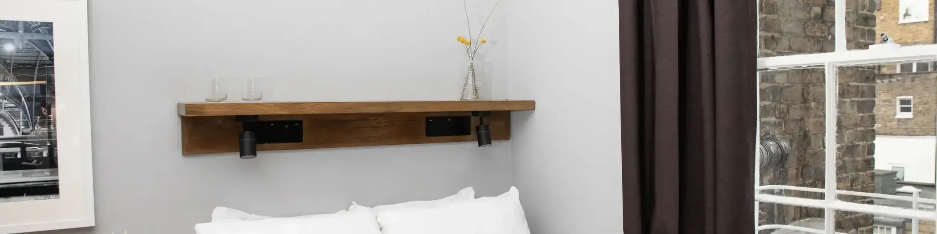 a bed with white sheets and brown curtains