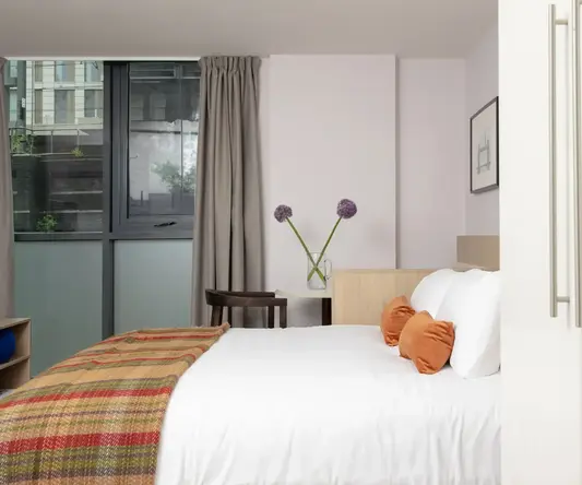 a bed with pillows and a blanket in a room with windows