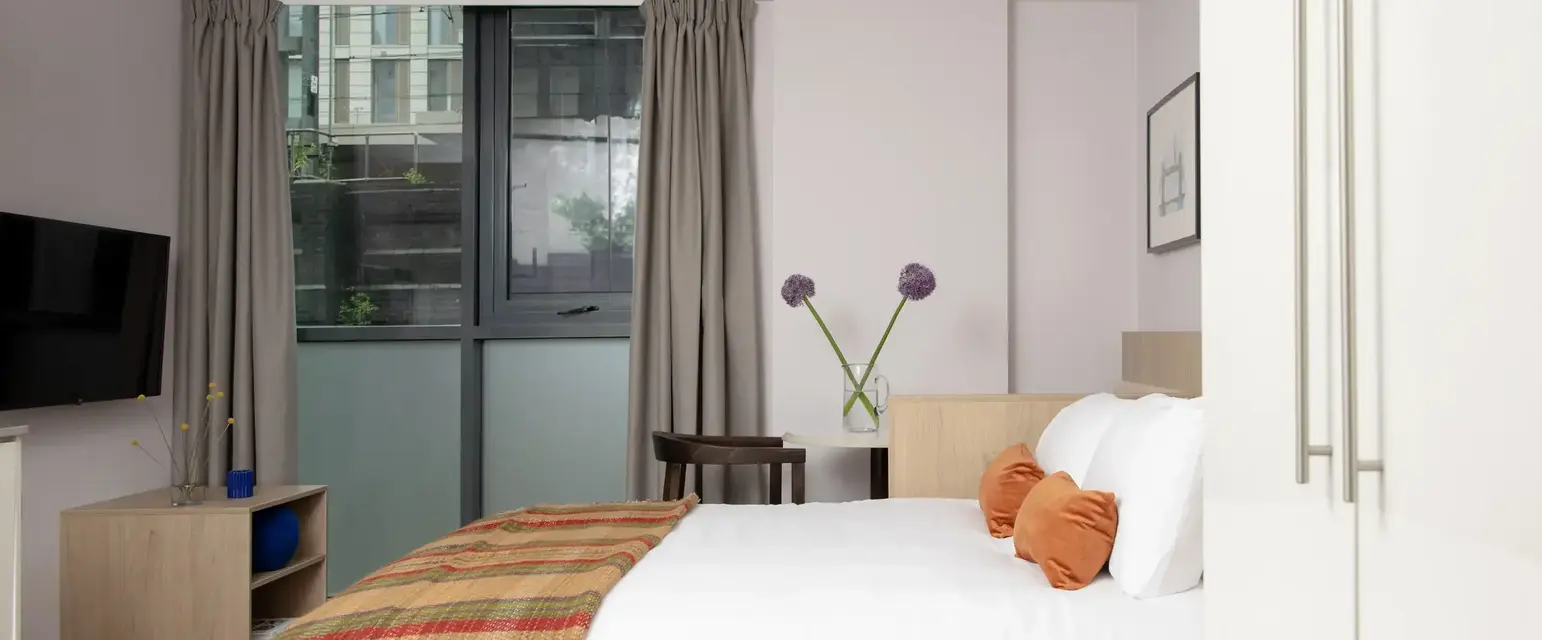 a bed with pillows and a blanket in a room with windows