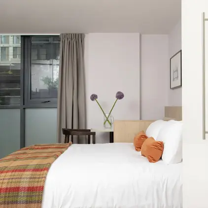 a bed with pillows and a blanket in a room with windows