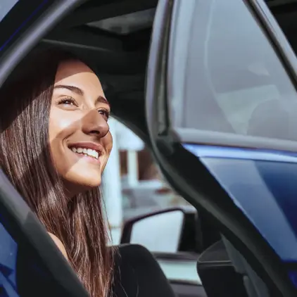 a woman smiling and looking out of a car door
