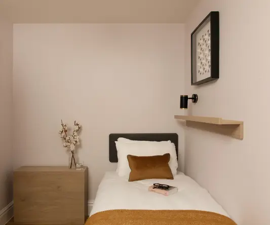 a small bed with a book and a vase of flowers on it