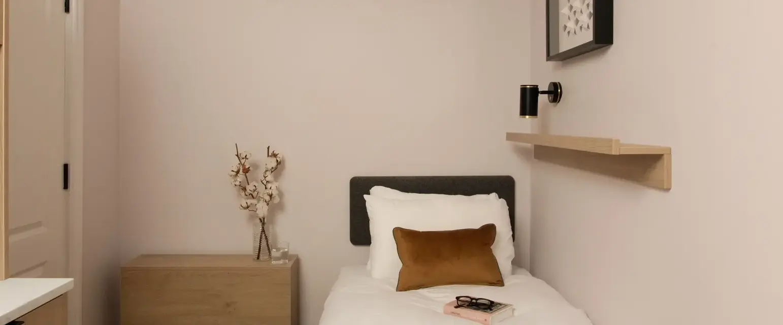 a small bed with a book and a vase of flowers on it