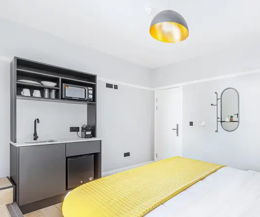 a bed with a yellow blanket and a microwave