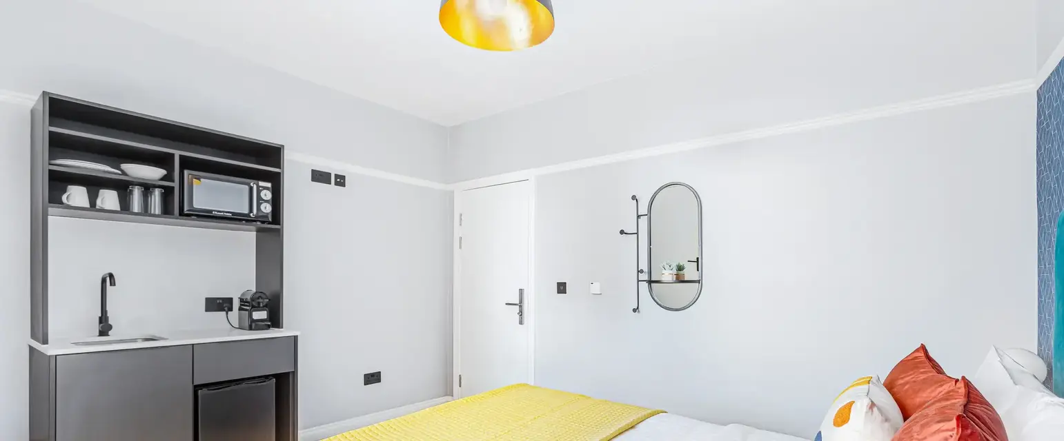 a bed with a yellow blanket and a microwave