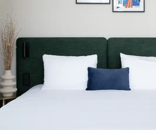 a bed with white sheets and pillows